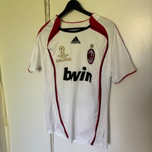 AC Milan tröja - Hej! Säljer en fet AC Milan bortatröja med Champions league badge, från säsongen 06/07. Denna har kaka på ryggen och är i fint skick, hör av er vid frågor!