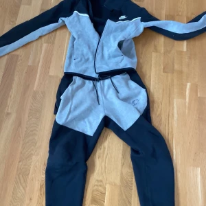 Grå och svarta mjukisbyxor från Nike - Nike tech fleece byxorna är i storlek M och tröjan i storlek XS. Är hål i fickan på tröjan och Nike märket är förstört på byxorna 