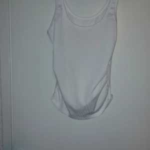 Vit ribbad linnetopp - Säljer en enkel och stilren vit linnetopp med ribbad struktur. Toppen är ärmlös och har en rund halsringning. Perfekt att matcha med jeans eller kjol för en avslappnad look.Endast tvättad.