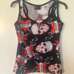 Svart linne med dödskallar och hjärtan från Insanity S/M - Helt nytt  linne fr Insanity. Storlek S/M. Lite stretchigt.