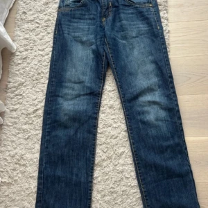 Blå jeansbyxor från NKDS.372 - Säljer ett par klassiska blå jeansbyxor från NKDS med raka ben och normal passform. Jeansen har fem fickor, dragkedja och knapp framtill samt snygga slitningar på låren. 