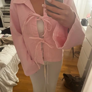 Ljusrosa denimjacka med knyt - Säljer en ljusrosa denimjacka som man även kan ha som tröja.  Från ginatricot, aldrig använd med lappen kvar. Köpt för 499, säljer för 399