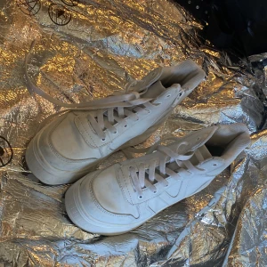 Vita höga sneakers med snörning - Säljer ett par klassiska vita höga sneakers med snörning och platt sula. Skorna har en stilren design med rund tå och är perfekta för dig som gillar en clean look. Passar till det mesta och är lätta att matcha.