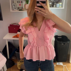 Rosa volangblus med knappar - Supersöt ljusrosa blus med volanger i strl S vet inte märke, säljer för att jag tyckte den va lite för stor! Nyskick fick av min kompis för den inte passa henne men passade tyvärr inte mig heller🙁 Hör bara av er om ni undrar något🥰