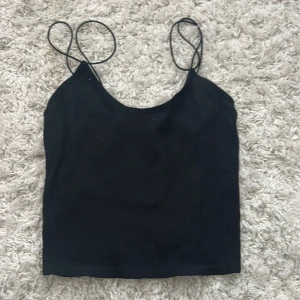 Svart linnetopp från Zara - Enkel och stilren svart linnetopp från Zara med tunna axelband och rak passform. Perfekt att matcha med jeans eller kjol för en clean look. Toppens material känns mjukt och lätt mot huden.