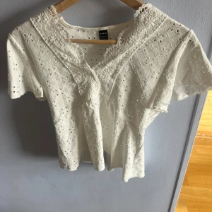 Vit spetsblus  - Supersöt vit blus från SHEIN i storlek M med broderade detaljer och spets runt v-ringningen. Blusen har korta ärmar och ett genombrutet mönster. Säljer då jag inte tyckte den satt så bra på just mig!! Storlek m men passar mig som S/xs