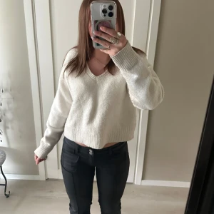 Vit stickad v-ringad tröja BikBok - Säljer en vit stickad tröja från BikBok i storlek XS. Tröjan är croppad med v-ringad hals och har långa ärmar. Den är mjuk och har ribbade muddar vid ärmslut och nederkant. Perfekt för dig som gillar enkel och clean stil.