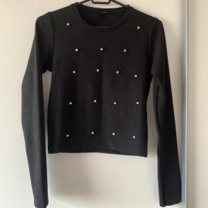 Svart stickad tröja med diamanter  - Svart stickad tröja med lång ärm och rund hals. Tröjan har diamanter på framsidan som ger en extra touch. Helt ny! Passar mer som xs.