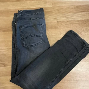 Wrangler gråa jeans slim fit - Snygga svarta Replay Anbass jeans med slim fit och klassisk femficksdesign. Jeansen har en mörk tvätt med lätt slitning och raka ben. Materialet är mjukt och stretchigt denim som sitter skönt hela dagen. Perfekt för dig som gillar stilrena och moderna jeans.