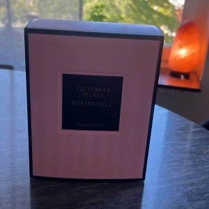 Victoria's Secret Bombshell parfym - Helt ny oanvänd! Bombshell Eau de Parfum från Victoria's Secret i en lyxig, multifasetterad glasflaska med rosa ton och elegant svart band runt halsen. Kommer i en snygg rosa kartong med svart detalj. Flaskan rymmer 100 ml och har en kristalliknande kork. Kvitto finns.