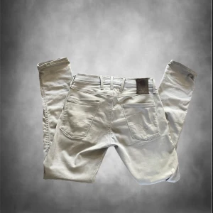 Replay Hyperflex Anbass ljusa jeans - Säljer ett par Replay Hyperflex Anbass jeans i ljusgrå färg. De har klassisk femficksdesign, smal passform och stretchigt material som gör dem riktigt sköna. Snygga detaljer med Replay-logga på fickan och bakre läderpatch. Perfekta för dig som gillar stilrena och bekväma jeans. Det finns synliga defekter på ena benet skriv för mer bilder!