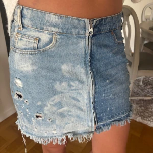 Blå jeanskjol med slitningar - Jeans kjol med två blåa färger, dragkedja och slitningar. Skulle säga storlek S
