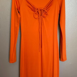 Gina Tricot klänning orange knytdetalj långärmad strl M - Trendig klänning från Gina Tricot i klar orange/röd nyans.   Midilång modell med lång ärm, figurnära passform och knytdetalj vid byst.    Storlek: M Skick: Mycket fint skick, knappt använd.   Nypris ca 300 kr.    Perfekt till vardag och fest.