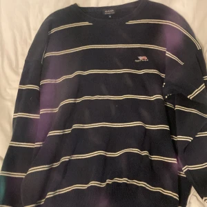 Randig marinblå tröja från GANT XL - Säljer en klassisk marinblå tröja från GANT i storlek XL. Tröjan har vita horisontella ränder och en broderad amerikansk flagga med GANT U.S.A på bröstet. Tillverkad i 100% kammad bomull, med rund hals och långa ärmar. Perfekt för dig som gillar preppy stil.