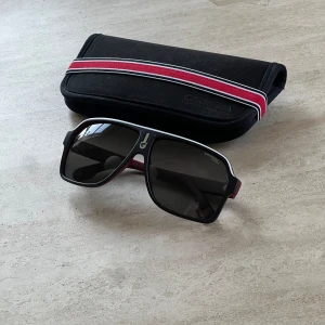 Carrera solglasögon 1001/S BLX/90 - Säljer nu mina Carrera glasögon då jag har ett par andra jag använder mer. De är knappt använda alltså bra skick förutom några repor på vänster glas då jag råkat repa dem med nyckelknippan en gång. Fodral kommer med. 