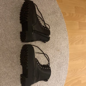 Svarta boots från H&M med snörning - Säljer ett par svarta boots från H&M i storlek 38. Skorna har grov platt sula, snörning framtill och dragkedja på sidan.
