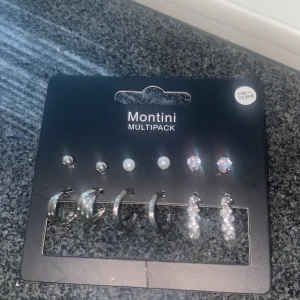 Montini multipack örhängen silver - Multipack med sex par örhängen från Montini i silverfärg. Innehåller små studs, pärlstuds, glittriga stenar och hoops i olika storlekar samt ett par hängande örhängen med pärlor. Perfekt för att mixa och matcha till din stil.