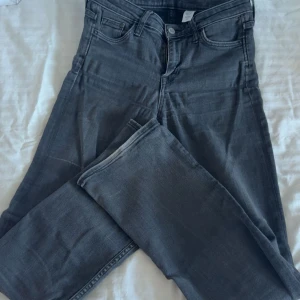 Mörkgrå raka jeans - Snygga mörkgrå jeans med klassisk femficksdesign och raka ben. Jeansen har låg midja och är tillverkade i mjukt denimtyg som ger en skön passform. Perfekta för dig som gillar en enkel och stilren look.