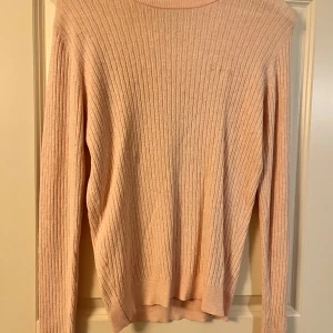 Ljusrosa stickad tröja Bondelid S - Supersöt ljusrosa stickad tröja från Bondelid i storlek S. Tröjan har ett klassiskt kabelstickat mönster, rund halsringning och långa ärmar. Perfekt för lager-på-lager och passar till både jeans och kjol.