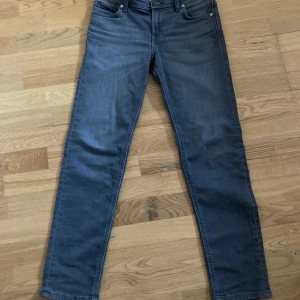 Mörkgrå jeans från Jack & Jones - Snygga mörkgrå jeans från Jack & Jones med klassisk femficksdesign och raka ben. Jeansen har diskret bakficka med broderad detalj och svart läderpatch i midjan. Perfekta för dig som gillar stilrena och enkla jeans i stretchig bomull.