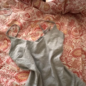 grått linne! - Ett vanligt grått linne. Men smala band och halv v-neck. Sitter bra och har dubbel skydd upptill.