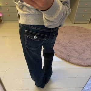 Mörkblå jeans med fickdetalj - Mörkblå jeans med lös passform, benen är lätt bootcut mot det rakare hållet. Supersköna och perfekta till vardags med en hoodie eller t-shirt. Knappt använda, i nytt skick utan defekter. 🥰Pris kan diskuteras!!!