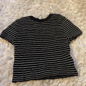 Svartvit stickad topp från H&M - Svart stickad topp från H&M med vita horisontella ränder. Toppen har korta ärmar, ribbad rund halsringning. Är super stretchig så skulle mer säga passar 12-14. Andvänt 2 gånger