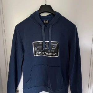 Emporio armani hoodie blå - Säljer nu min riktigt snygga emporio armani hoodie då den inte längre passar. Hoodien är storlek M men passar som S. Endast använd ett fåtal gånger. Kan gå ner i pris vid snabb affär. Kom med frågor!