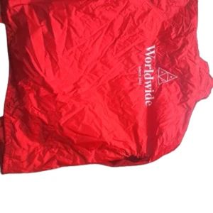 Röd vindjacka Worldwide med tryck - Riktigt snygg röd vindjacka från Worldwide med vitt tryck på bröstet och ryggen. Jackan har knappar framtill, dragsko nertill och långa ärmar med resår vid handlederna. Perfekt för dig som vill sticka ut med en färgstark look.