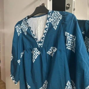 Blå blus med vit broderi - strl S-M - Säljer en blå/vit blus som jag endast använt en gång. väldigt luftig och skön. 💓