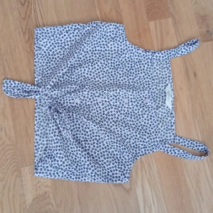 Vit leopardmönstrad linnetopp H&M - Säljer en söt vit linnetopp från H&M med blått leopardmönster. Toppen har smala axelband och en knytning framtill som ger en chill vibe. Perfekt för varma dagar och enkel att matcha med jeans eller shorts.