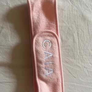 Rosa frotté diadem från CAIA - Säljer ett mjukt och brett diadem från CAIA i ljusrosa frotté med vit broderad logga framtill. Perfekt när du vill hålla håret borta vid sminkning eller hudvård. Snygg och enkel design som känns fräsch i badrumshyllan.