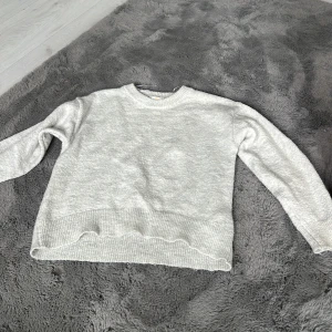 Ljusgrå stickad tröja Gina Tricot - Supermjuk ljusgrå stickad tröja från Gina Tricot med rund halsringning och ribbade muddar. Perfekt för lager-på-lager och chill dagar. Enkel och stilren design som funkar till allt. Snygg vågig kant nedtill för en extra touch.