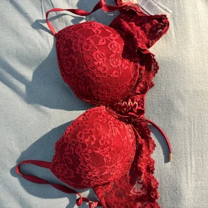 Vinröd spets BH med snörning - Superfin vinröd korsett med vacker spets och snygg snörning framtill. Axelbandslös design och detaljer i guld på snörningen. Perfekt för dig som vill ha något extra och romantiskt i garderoben.