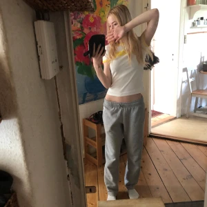 Vit och gul t-shirt med tryck - Säljer en vit t-shirt med gula detaljer vid hals och ärmslut samt gul texten 'Mi Amore' på bröstet. Modellen är kortärmad och har en slim passform som sitter tajt. Perfekt för dig som gillar retrovibbar och färgglada detaljer.