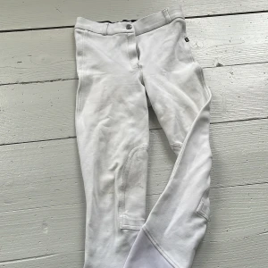 Vita ridbyxor från CRW, stl 34 - Snygga vita ridbyxor från CRW med förstärkta knäpartier och bekväm midja. Byxorna har klassisk passform och är perfekta för dig som gillar att tävla inom ridning. Materialet är mjukt och stretchigt för bästa rörelsefrihet. Dom har lite smuts/förg från sadeln vid knäna som inte går bort i tvätten men det syns inte bör man rider eller knappt alls (priset är 150 men går att diskuteras vid snabbt och smidigt köp)