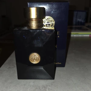 Versace Dylan Blue Pour Homme 100ml - Versace Dylan Blue Pour Homme är en maskulin parfym i en lyxig mörkblå glasflaska med guldiga detaljer och Versaces ikoniska Medusa-logga. Flaskan rymmer 100 ml och har en elegant, fyrkantig form med en tung guldfärgad kork. Perfekt för dig som gillar exklusiva dofter.