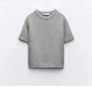 Grå stickad kortärmad tröja Zara - Supermjuk grå stickad tröja från Zara med korta ärmar och rund halsringning. Perfekt för lager-på-lager och funkar lika bra till jeans som kjol. Enkel och stilren design som passar till allt.