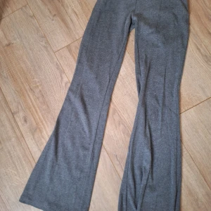 Grå bootcut byxor från Lindex - Snygga grå bootcut byxor från Lindex i mjukt och stretchigt material. Byxorna har utsvängda ben, perfekta för en trendig och bekväm look. Passar dig som gillar en avslappnad men ändå stilren stil.
