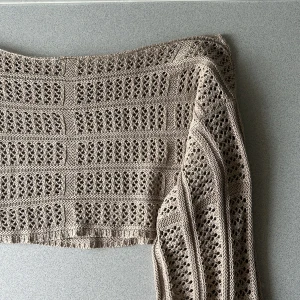 Beige stickad croppad tröja - Säljer en beige stickad croppad tröja med lång utsvängd ärm. Tröjan har ett luftigt, hålmönstrat stickat mönster som ger en cool och avslappnad vibe. Superfin, dock för liten på mig! Passar perfekt under t.ex bikini eller som strandkläder! Använd gärna Early Bird som fraktalternativ.