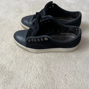 Svarta sneakers från Valentino - Snygga svarta sneakers från Valentino med ovandel i mocka och tåparti i skinn. Skorna har vita sulor och metallfärgade öljetter för snörning. Perfekta för dig som gillar stilrena och exklusiva sneakers med en lyxig känsla.