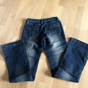 Mörkblå jeans från Forbidden - Snygga mörkblå jeans från Forbidden med slitningar och markerade sömmar. Modellen har raka ben, klassiska fem fickor och en tydlig dragkedja framtill. Bakfickorna har dekorativa sömmar. Skriv om frågor!