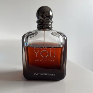 Emporio Armani Stronger With You - Emporio Armani Stronger With You Absolutely är en parfym med en elegant, mörkbrun glasflaska och rundad silverfärgad kork. Doften är intensiv och modern, perfekt för dig som gillar en djup och varm känsla. Flaskan har stilren design med märkets logga framtill.