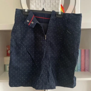 Mörkblå prickiga shorts Peak Performance - Snygga mörkblå shorts från Peak Performance med små vita prickar. Klassisk passform med dragkedja och knapp, bälteshällor och flera fickor. Perfekta för sommaren och riktigt sköna i bomull. Stilsäkra detaljer som röd rand på insidan av linningen.