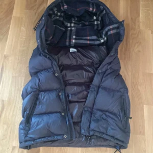 Burberry väst - Säljer denna mörkblåa burberry västen(äkta)västen har tyvär inga armar vilket betyder att BARA VÄSTEN KOMMER MED.Den är perfekt till sommarkvällar eller under en Hoodie storlek M men passar till S också,Lite defekter på baksidan och dragkedjorna