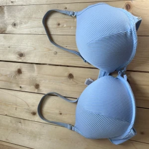 Ljusblå ribbad bh från Emporio - Snygg ljusblå bh från Emporio med ribbad struktur och justerbara axelband. Kuporna är vadderade och ger bra stöd. Perfekt för dig som gillar en enkel men stilren look.