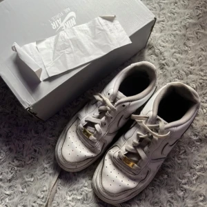 Nike Air Force 1 vita sneakers - Air force 1 vita som kommer med kvittot och lådan, Dem har lite defekter som ena skon har tyget åkt av lite vid snörena. och har lite rosa färg som syns knappt. annars är dem i bra skick!! priset går diskuteras!