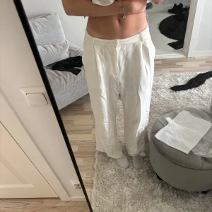 Vita vida linnebyxor - Säljer ett par fräscha vita linnebyxor med vida ben. Byxorna har hällor för bälte, diskreta fickor bak och stängs framtill. Perfekta för en chill och stilren look under varmare dagar.
