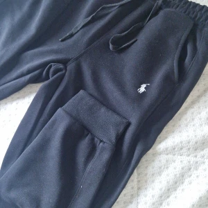 Svarta mjukisbyxor Polo Ralph Lauren - Svarta mjukisbyxor från Polo Ralph Lauren med klassisk broderad logga på benet. Byxorna har resår och snörning i midjan samt muddar vid bensluten. Tillverkade i mjukt bomullsmaterial för maximal komfort. Storlek S men passar även xs. En skön material som är väldigt mjuk.