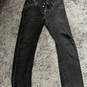 Levi's 501 svarta jeans W30 L32 - Mörkgrå/washed black Levis jeans i modellen 501. Sitter as snyggt men tyvärr har de blivit lite försmå på mig. Mycket bra skick den enda skavanken är att ett av bälteshålen har lossnat men det är en enkel fix, därav det lägre priset. Hör gärna av dig vid frågor!